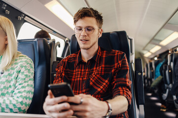 A traveler on train with cellphone choosing music for a journey.