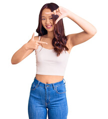 Young beautiful chinese girl wearing casual clothes smiling making frame with hands and fingers with happy face. creativity and photography concept.