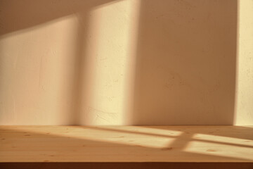 Empty wooden table on stucco brown background with natural shadow on the wall. Mock up for branding...