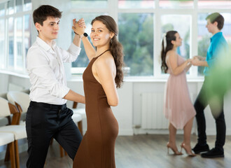 Young man and young woman dance ballroom dance waltz in studio