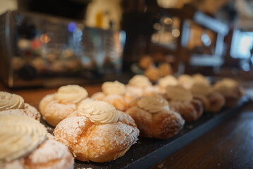 Close up view of cream filled pastries dusted with powdered sugar, decorated with a swirl of cream,...