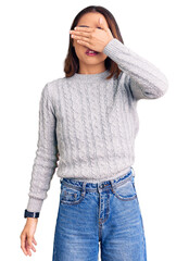 Young beautiful chinese girl wearing casual clothes covering eyes with hand, looking serious and...