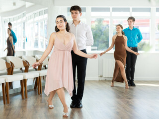 Couple of young guy and young woman dancing waltz in studio