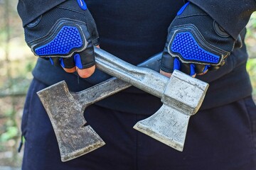 two small iron old sharp dangerous hatchets are held in the hands of an aggressive man during the...