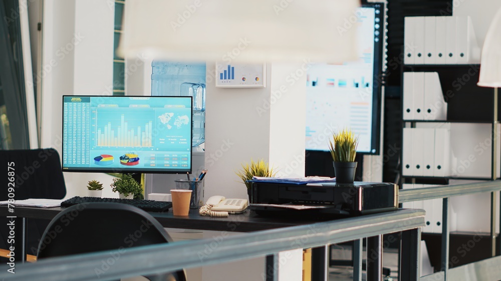 Poster office with computer monitor on desk showing stock exchange listings and display in background with 