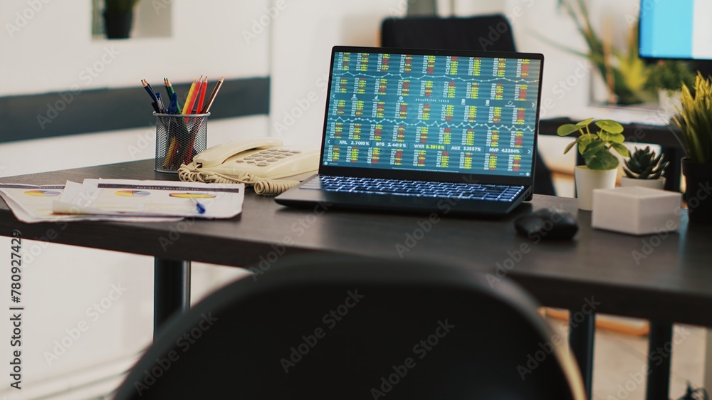 Aufkleber company paperwork and laptop with stock market data collected in office to develop trading strategie