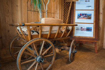 Vintage wooden cart with firewood on brown carpet indoors, hints of spa and mountain view in background, possible French speaking area resort or lodge lobby aesthetic.
