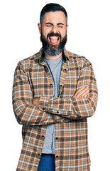 Fototapeta premium Hispanic man with beard with arms crossed gesture sticking tongue out happy with funny expression.