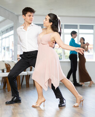 Young couples learning to dance latin american dances in a dance studio