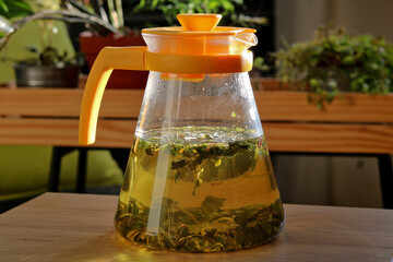 Tea pot with herbal tea in which herbs, leaves and flowers are infused