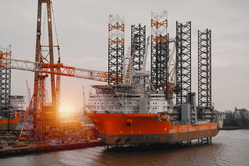 Wind Turbine Installation Vessel. Self-Elevating Vessel In The European Port During The Repairs On Deck. Offshore Support Construction Vessel Jacked Up.