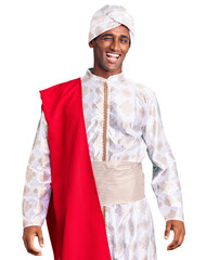 African handsome man wearing tradition sherwani saree clothes winking looking at the camera with sexy expression, cheerful and happy face.