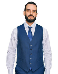 Young man with beard wearing business vest relaxed with serious expression on face. simple and natural looking at the camera.