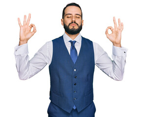 Young man with beard wearing business vest relax and smiling with eyes closed doing meditation gesture with fingers. yoga concept.