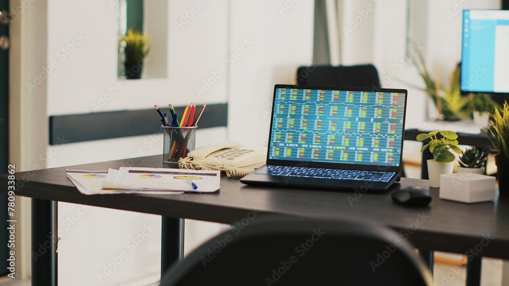 Poster laptop in company office shows stock exchange values changing in real time, panning shot. paperwork 
