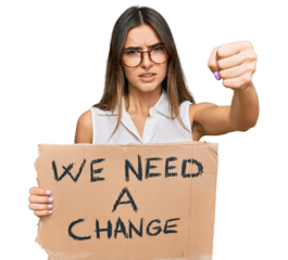 Young hispanic woman holding we need a change banner annoyed and frustrated shouting with anger, yelling crazy with anger and hand raised