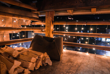 Indoor setting with rustic, cozy ambiance. Wooden box filled with firewood in foreground, warm...