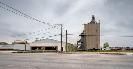 Grain elevator with abandoned building and abandoned vehicles in the town of Seagraves, Texas, United States