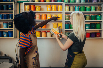 Rear view of interracial graphic workers choosing paint buckets at workshop