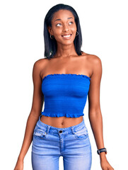 Young african american woman wearing casual summer clothes looking away to side with smile on face, natural expression. laughing confident.