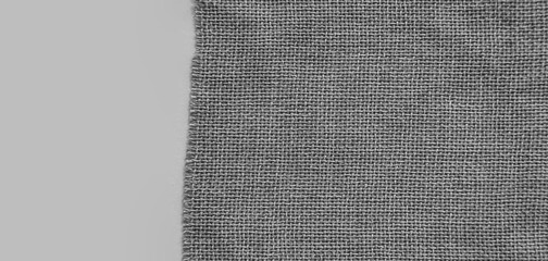texture of the natural fabric of gray color. Natural fabric with a clear interweaving of threads. Everyday stuff. Burlap texture. A piece of torn burlap on a white background. Canvas. Packing material