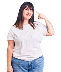 Obraz premium Young plus size woman wearing casual clothes smiling pointing to head with one finger, great idea or thought, good memory