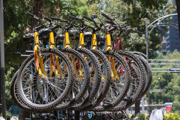 row of bicycles parked on a city street, rental bicycle parking, means of transportation