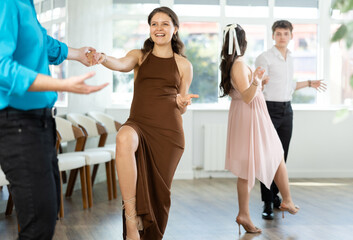 Couples in evening dresses suits enjoys pair dance boogie-woogie, positively interacting with each...