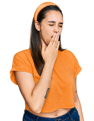 Young hispanic woman wearing casual clothes bored yawning tired covering mouth with hand. restless...