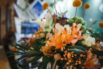 Colorful floral arrangement featuring vibrant orange lilies, small orange flowers, yellow button...