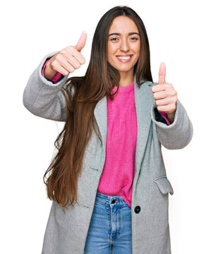 Young hispanic girl wearing business clothes approving doing positive gesture with hand, thumbs up smiling and happy for success. winner gesture.