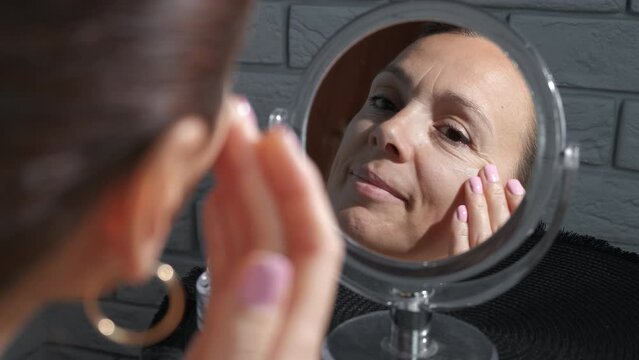 Apply face cream for skin care against mirror. A woman applying cosmetic cream on her face to be nice in the morning.
