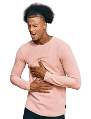 African american man with afro hair wearing casual clothes with hand on stomach because nausea,...