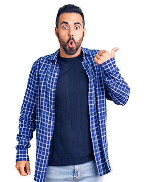 Young hispanic man wearing casual clothes surprised pointing with hand finger to the side, open mouth amazed expression.