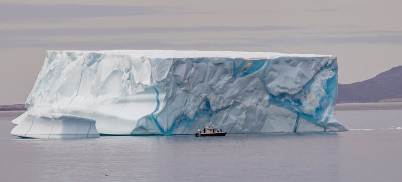 huge Iceberg in Greenland harbor with boat for size comparison