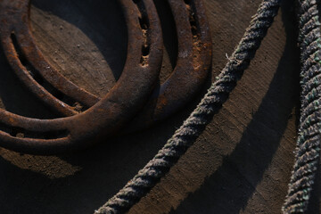Old vintage western art background with rustic horseshoes and rope as flat lay.
