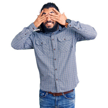 Young arab man wearing casual clothes covering eyes with hands smiling cheerful and funny. blind concept.