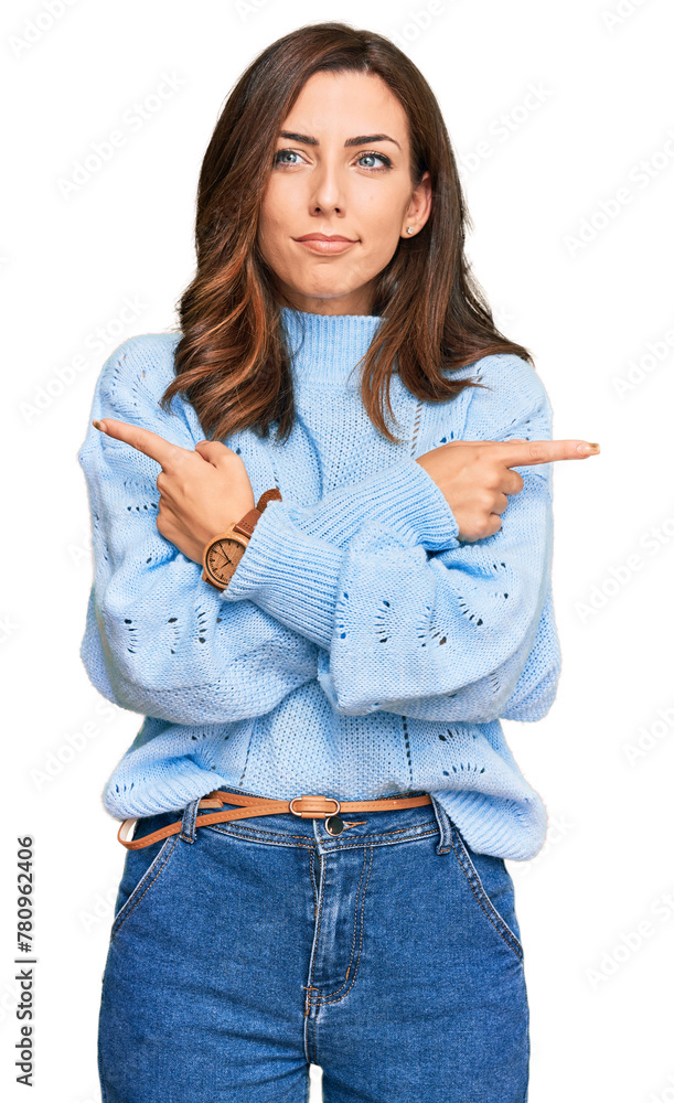 Wall mural Young brunette woman wearing casual winter sweater pointing to both sides with fingers, different direction disagree