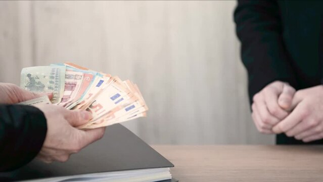 Transfer of money from hand to hand and a folder with documents. Cash payment for the services of a lawyer, attorney, accountant. Giving and accepting a bribe
