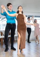 Fototapeta premium Enthusiastic young couple, elegant guy and attractive girl in formal wear, performing kizomba in studio class setting, demonstrating dance characteristic sensual and connected movements..