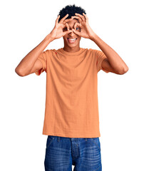 Fototapeta premium Young african american man wearing casual clothes doing ok gesture like binoculars sticking tongue out, eyes looking through fingers. crazy expression.