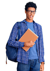 Young african american man wearing student backpack holding book winking looking at the camera with sexy expression, cheerful and happy face.