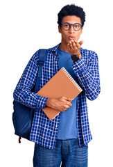 Young african american man wearing student backpack holding book looking at the camera blowing a kiss with hand on air being lovely and sexy. love expression.