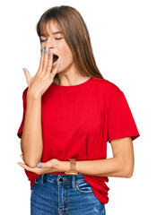 Teenager caucasian girl wearing casual red t shirt bored yawning tired covering mouth with hand. restless and sleepiness.