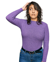 Young hispanic woman wearing casual clothes confuse and wonder about question. uncertain with...