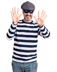 Naklejka premium Middle age handsome man wearing burglar mask showing and pointing up with fingers number ten while smiling confident and happy.