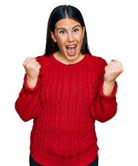 Beautiful brunette woman wearing casual sweater screaming proud, celebrating victory and success very excited with raised arms