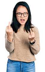 Young chinese woman wearing casual sweater and glasses showing middle finger doing fuck you bad expression, provocation and rude attitude. screaming excited