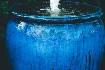 A blue ceramic vase with water flowing