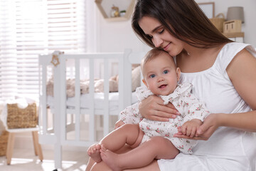 Happy young mother with her baby daughter in nursery. Space for text